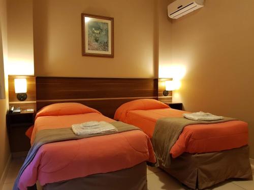 a hotel room with two beds with orange sheets at Astro Hotel in São José dos Campos