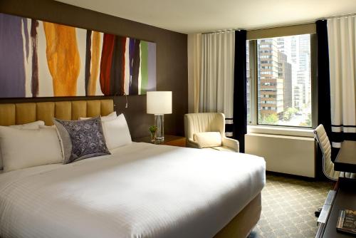 um quarto de hotel com uma cama grande e uma janela em The Fifty Sonesta Hotel New York em Nova Iorque