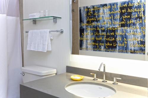a bathroom with a sink and a toilet and a mirror at The Fifty Sonesta Hotel New York in New York
