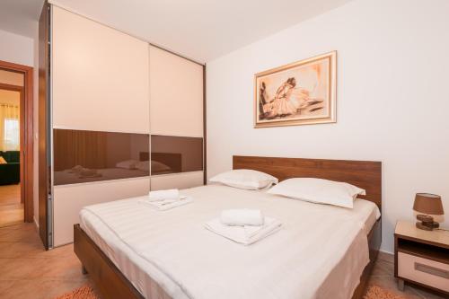 a bedroom with a large white bed with two towels on it at Family Apartment Dubrovnik - private jacuzzi terrace, private parking in Dubrovnik