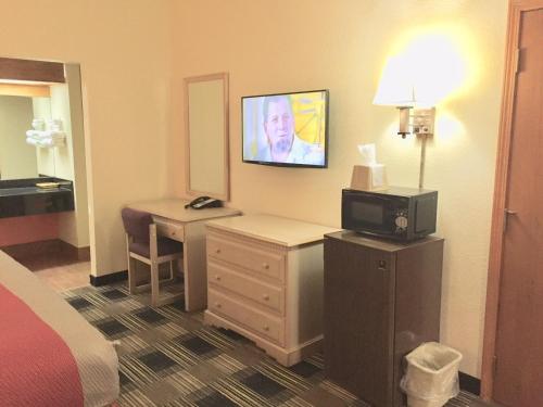 a hotel room with a bed and a desk with a television at Red Carpet Inn North Chicago in North Chicago