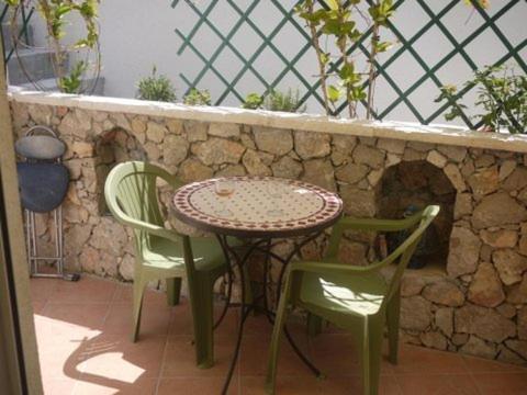 d'une table, de chaises et d'un mur en pierre. dans l'établissement Appartement Charme et Coeur, à Villefranche-sur-Mer