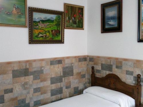 a bedroom with a bed and pictures on the wall at Alojamiento Los Poetas in Baeza