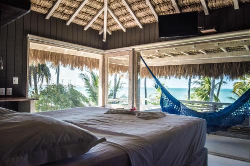 een slaapkamer met een hangmat en uitzicht op de oceaan bij DePraiaBrasil in Icaraí