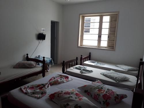 a group of three beds in a room with a window at Hotel Ideal Taubaté in Taubaté