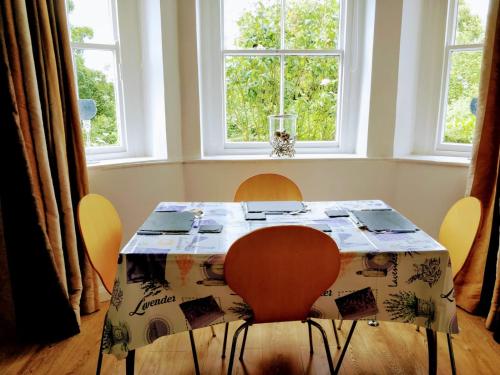 ein Tisch und Stühle mit einem Tisch und zwei Fenstern in der Unterkunft Riverbank Apartment in Derry Londonderry