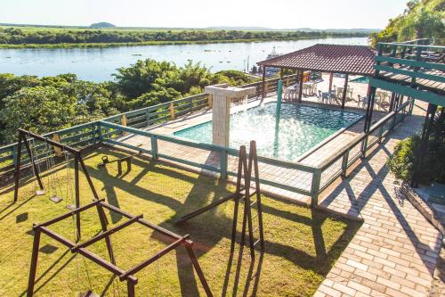 a swimming pool with a gazebo next to a river at Candeias Hotel Gold Fish in Corumbá