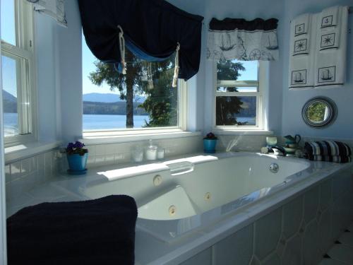 a large white tub in a bathroom with windows at The Oceanfront Inn on Stephens Bay in Coal Harbour