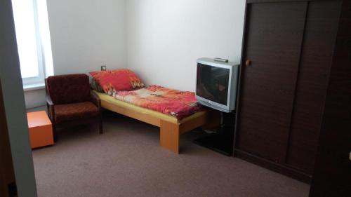 a room with a bed and a tv and a chair at Svit Dovolenkový dom in Svit