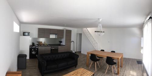 un salon avec un canapé noir et une table dans l'établissement Maison entière au pied des vignes, à Lussac