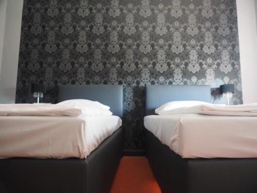 two beds in a room with a wallpaper at Hotel Kipphut in Sarstedt