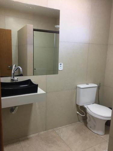 a bathroom with a toilet and a sink and a mirror at Hotel Paradizzo in Foz do Iguaçu