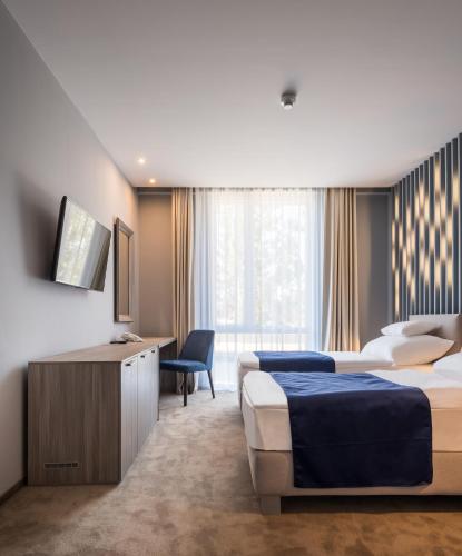 a hotel room with two beds and a television at Várda Sport Hotel in Kisvárda