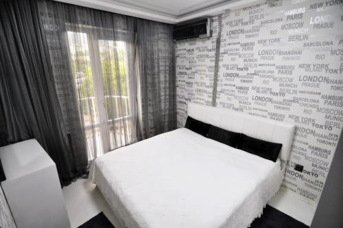a bedroom with a white bed and a brick wall at Hotel Chanel Apartments in Tbilisi City