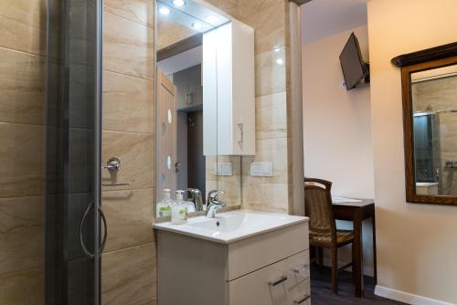 a bathroom with a sink and a shower with a mirror at Apartamenty Koba in Ustroń