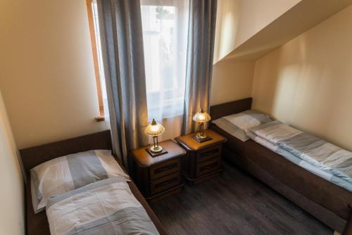 two beds in a room with two lamps on tables at Apartamenty Koba in Ustroń