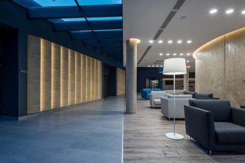 two images of a lobby with couches and chairs at Várda Sport Hotel in Kisvárda