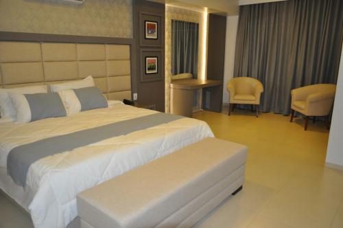 a hotel room with a large bed and chairs at Hospedare Hotel in Marechal Cândido Rondon