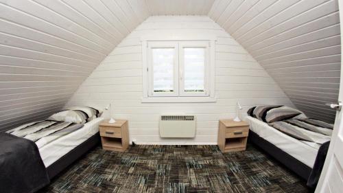 2 camas en una habitación blanca con ventana en Domki Letniskowe "Osada Grzybowo" en Grzybowo