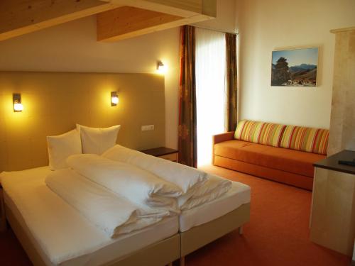 ein Schlafzimmer mit einem großen weißen Bett und einem Sofa in der Unterkunft alpinea Appartements in Ischgl
