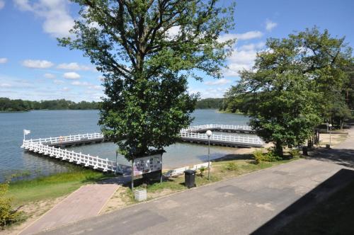 a dock on a river with a boat in the water at Pokoje hotelowe Nad jeziorem Jelen in Bytów