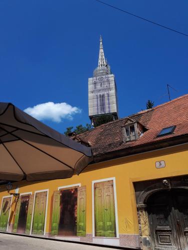 a yellow building with a clock tower in the background at Apartment History in Zagreb