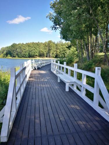a wooden bridge over a lake with a white fence at Pokoje hotelowe Nad jeziorem Jelen in Bytów