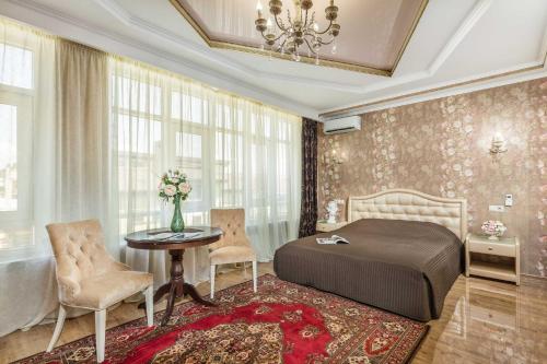 een slaapkamer met een bed en een tafel en stoelen bij Guest House Viva Viktoria in Novorossiejsk