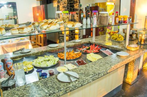 a buffet with many plates of food on a counter at Candeias Hotel Gold Fish in Corumbá