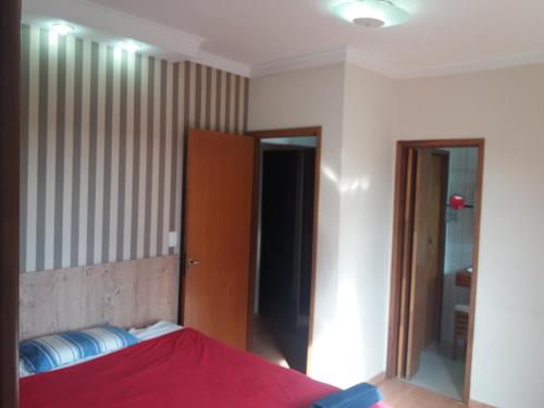1 dormitorio con cama roja y espejo en Residencial Castelo Branco, en Campinas
