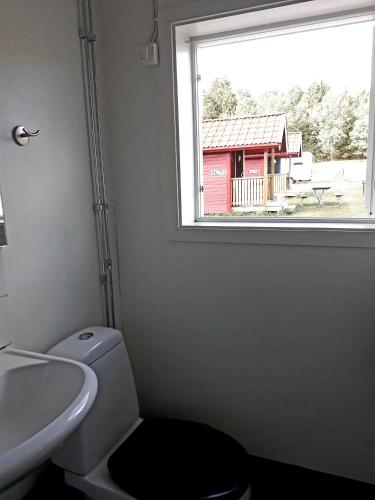 a bathroom with a toilet and a sink and a window at Älgbergets Bed & Breakfast in Ucklum