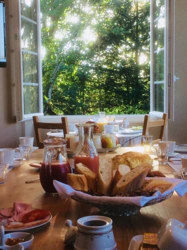 une table en bois avec une assiette de pain et une fenêtre dans l'établissement La Maison du Parc, aux Épesses
