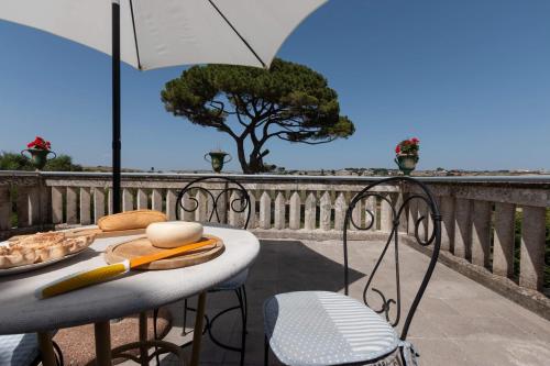 una mesa y sillas en un balcón con sombrilla en Villa Castiglione 1863 - The real Sicilian holiday, en Ragusa