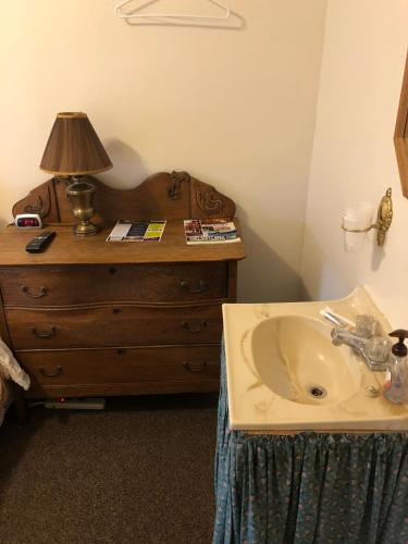 a bathroom with a sink and a lamp on a dresser at The Courtland Hotel & Spa in Fort Scott