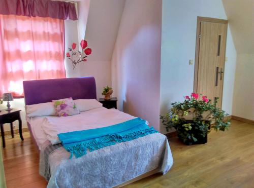 Motel Rezydent في فروتسواف: غرفة نوم مع سرير بورد أرجواني للرأس