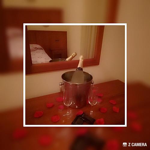 a bottle of champagne in a pot on a table with red roses at Hotel Reina Isabel in Lleida
