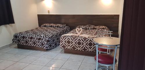 a bedroom with two beds and a table and a stool at Costa Miramar in Acapulco