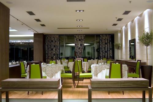a restaurant with green and white tables and chairs at Olympic Palace Hotel in Ixia