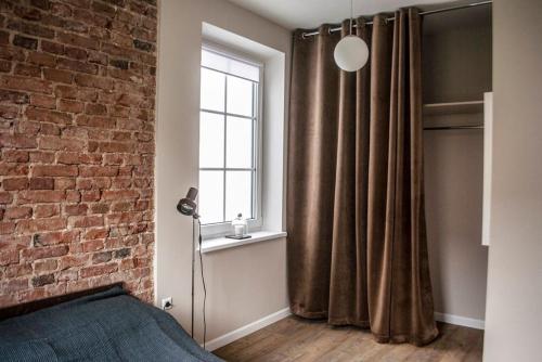 a bedroom with a brick wall and a window at Smartflat & New apartment city center in Kaunas
