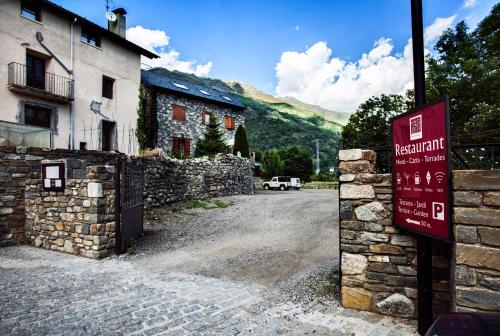 a sign in front of a building with a stone wall at Hostal La Plaça in Erill la Vall