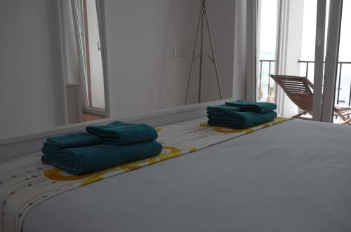 two green towels sitting on a bed in a room at Ocean View Suite in Paço de Arcos