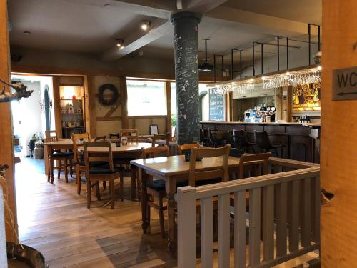 a restaurant with wooden tables and chairs and a bar at Hotel de Plank - alle kamers met airconditioning in Noorbeek