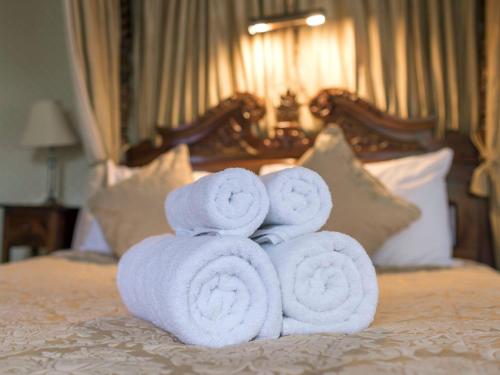 a pile of towels stacked on top of a bed at The Grange at Oborne in Sherborne