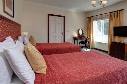 a hotel room with two beds and a television at The Grange at Oborne in Sherborne