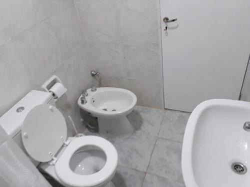 biała łazienka z toaletą i umywalką w obiekcie Aparthostel Cataratas del Iguazu w mieście Puerto Iguazú