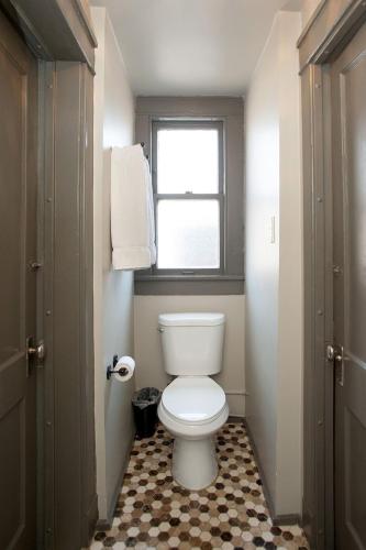 a bathroom with a white toilet and a window at Gardner Hotel & Hostel in El Paso