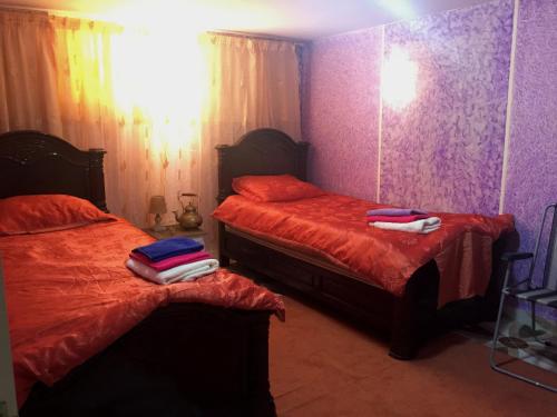 a bedroom with two beds with red sheets and purple walls at Naima appartment in Moulay Bousselham