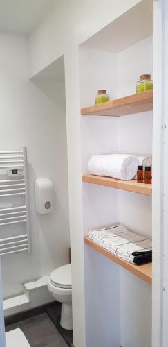 a white bathroom with a toilet and shelves at Val' Appart 1 in Valenciennes