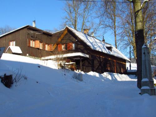 a large wooden house with snow on the ground at Chata u Kostela in Dolni Misecky