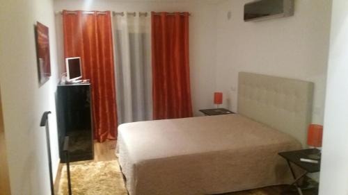 サン・マルティーニョ・ド・ポルトにあるMy Homeのオレンジ色のカーテンが備わるベッドルーム1室です。